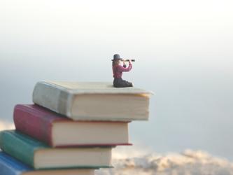 Woman with telescope sat on pile of books
